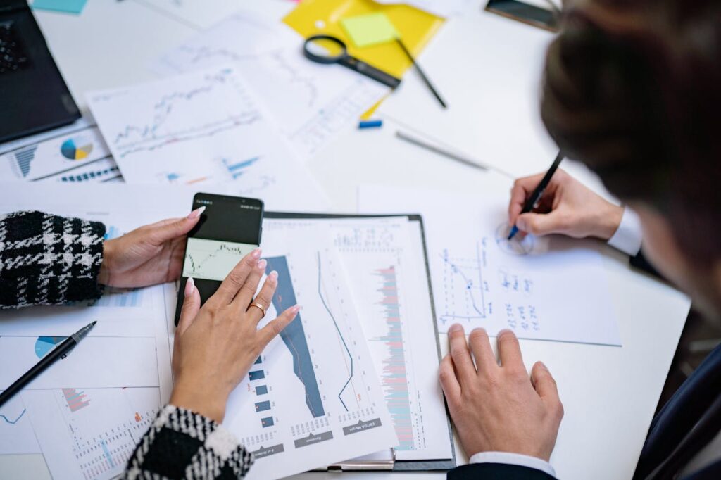 Crafting Captivating Headlines: Your awesome post title goes here Overhead view of people analyzing financial graphs and data with smartphone and documents.