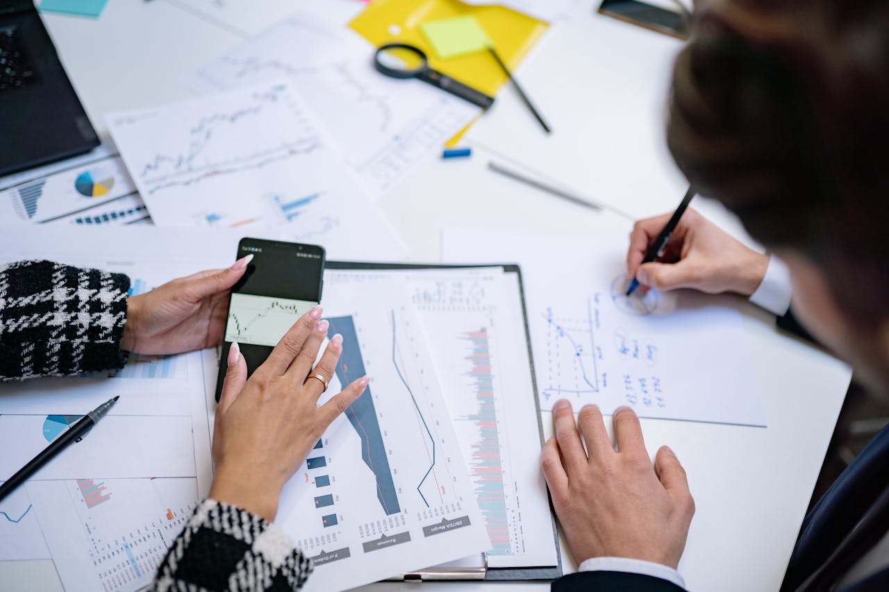 Crafting Captivating Headlines: Your awesome post title goes here Overhead view of people analyzing financial graphs and data with smartphone and documents.